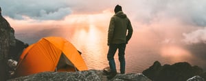 Person beim Campen in den Bergen. Mit Zelt bei Sonnenuntergang.